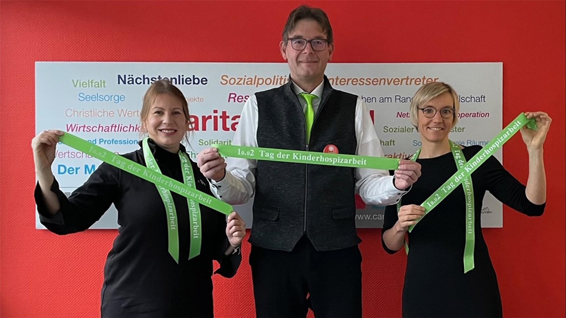 3 Personen halten das grüne Band in die Höhe