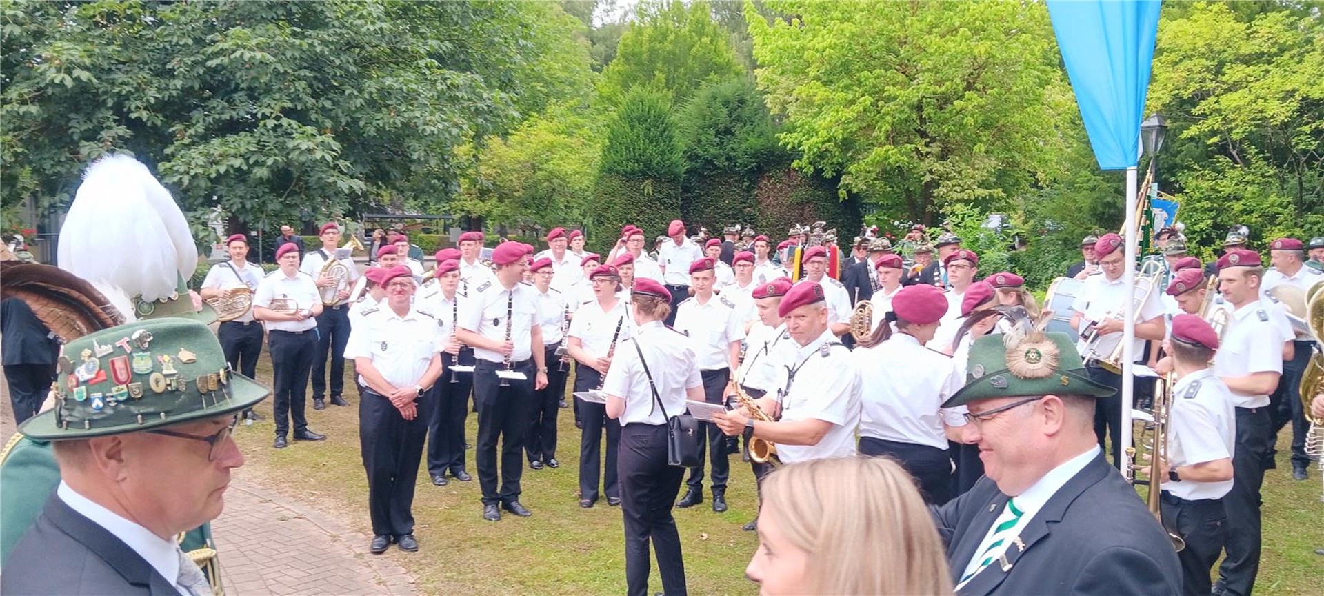 Musikerinnen und Musiker einer Schützenkapelle in Uniform versammeln sich während des Schützenfestes und bereiten sich gemeinsam auf ihren Auftritt vor.