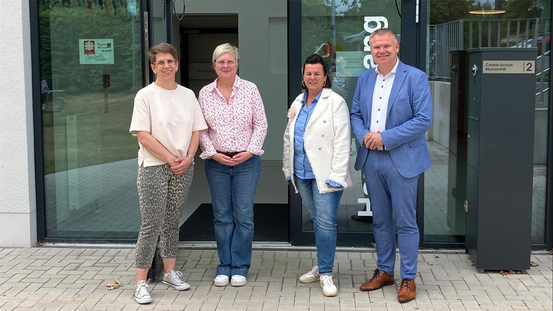 Thomas Grosche (CDU-Landratskandidat), Désirée Schinner (sozialpädagogische Fachkraft der Grundschule Medebach) und Alexandra Heiland-Kremer (Arnsberger Kreistagskandidatin) posieren vor dem Eingang der Caritas-Schule Mariannhill