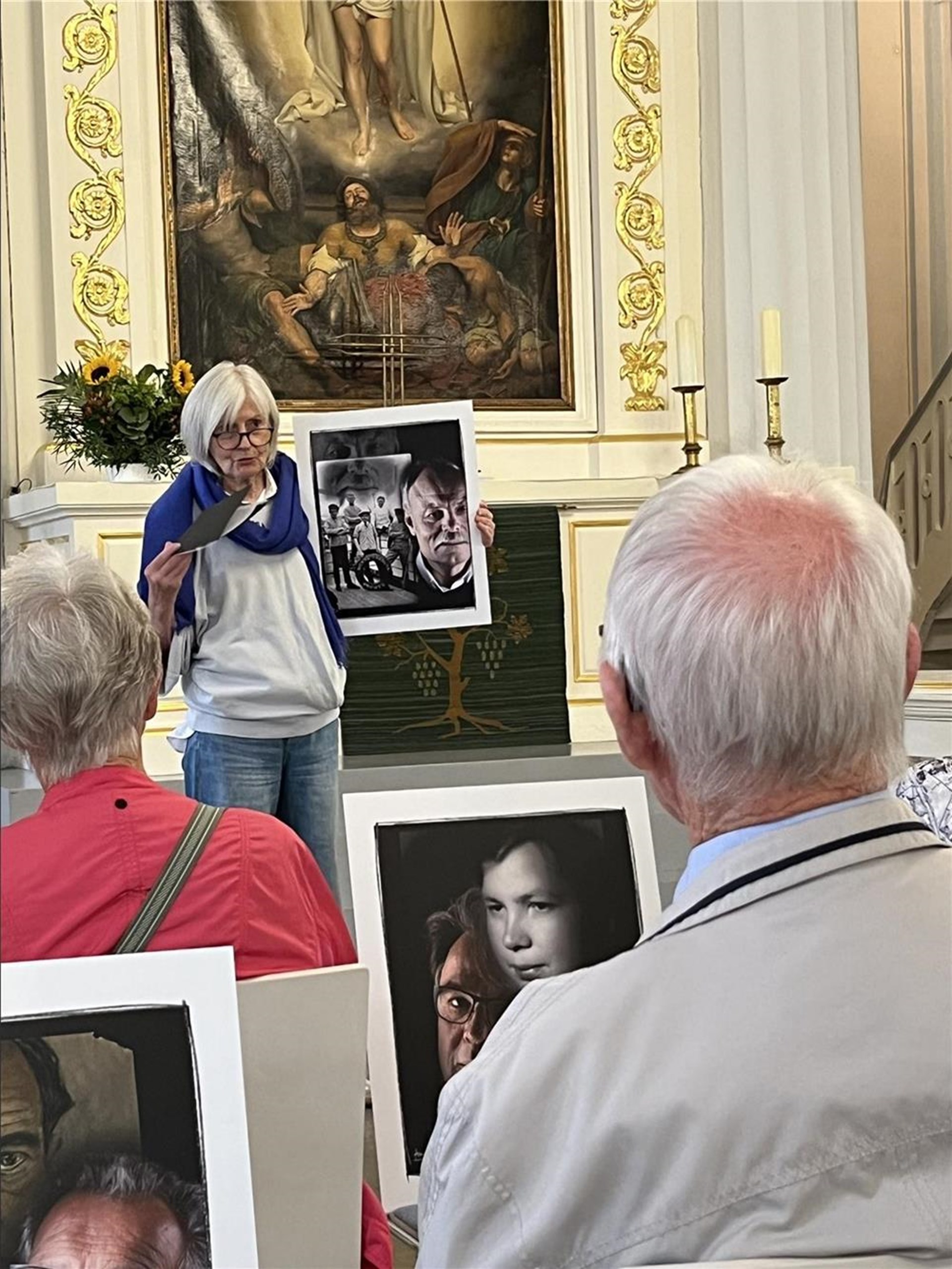 Die Künstlerin Barbara Anneser erläutert eines ihrer Werke während der Führung durch die Ausstellung „Memento Mori“. Die Besucher verfolgen ihre Erklärungen aufmerksam.