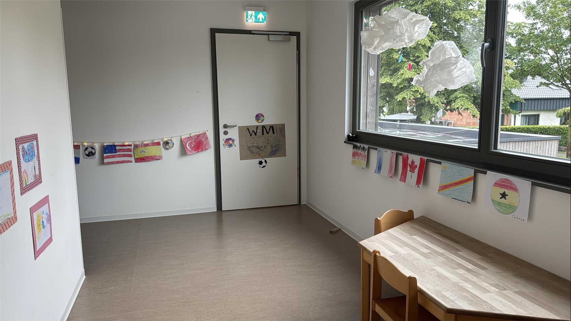 Ein Gruppenraum ist mit selbst gestalteten Flaggen, Fußballmotiven und einer WM-Dekoration geschmückt. Die bunte Gestaltung unterstreicht das Motto „Wir sind bunt“.