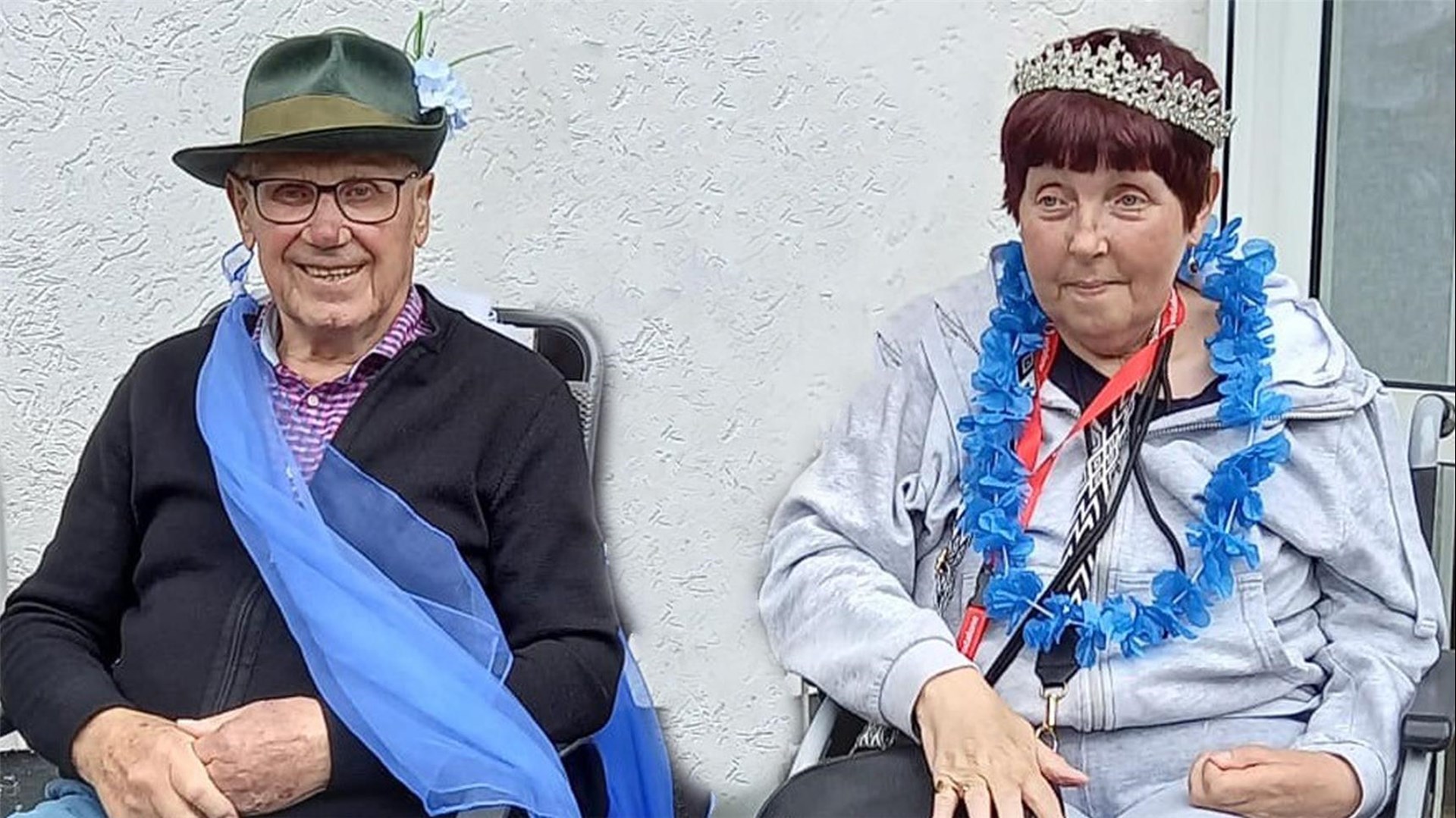 Der Schützenkönig mit Schützenhut und blauer Schärpe und die Schützenkönigin mit Diadem und blauer Blütenkette.  