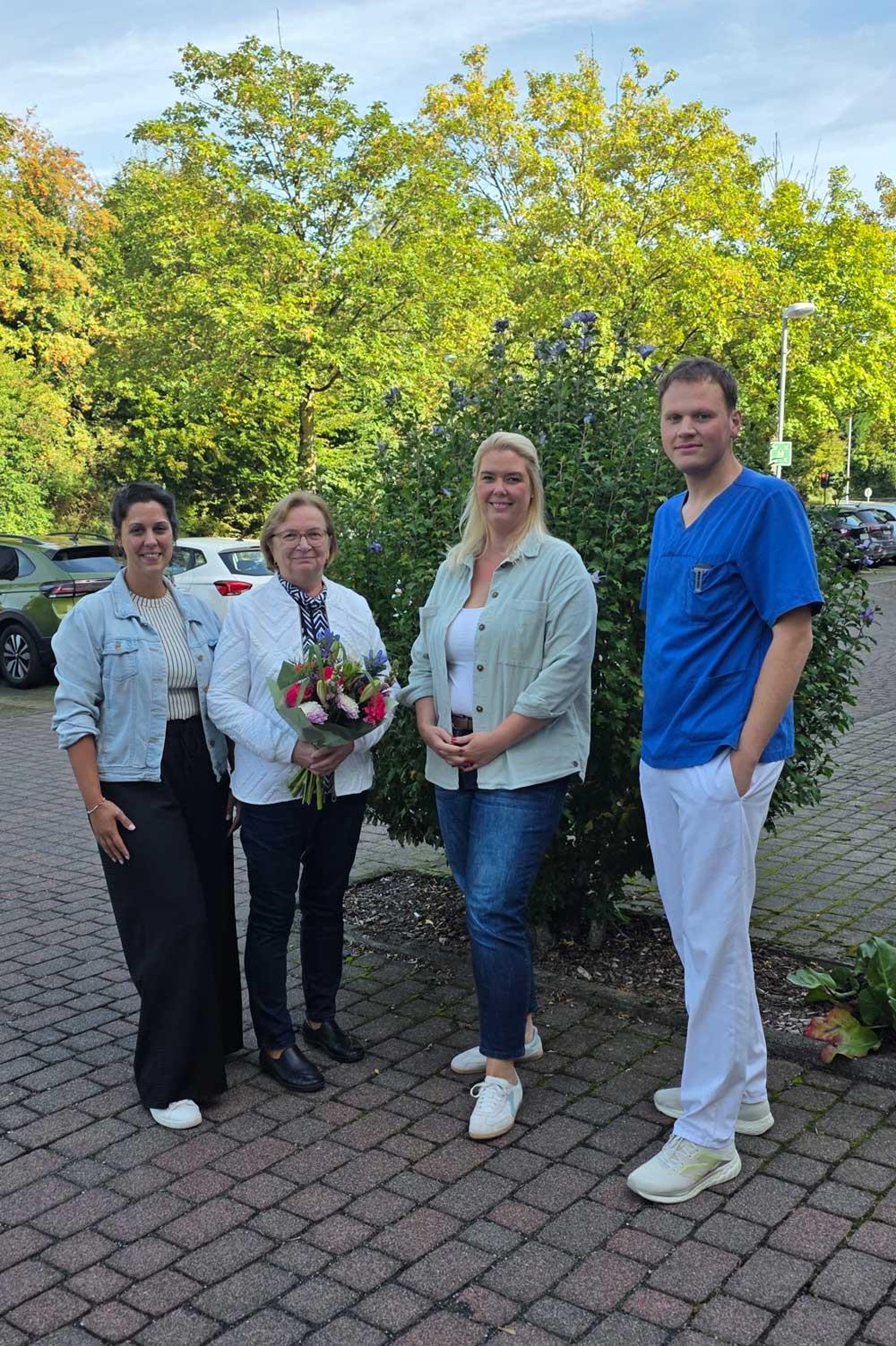 Vier Mitarbeitende des Seniorenhauses St. Josef stehen bei der Verabschiedung einer langjährigen Kollegin in den Ruhestand zusammen. Die verabschiedete Mitarbeiterin hält einen Blumenstrauß in den Händen.